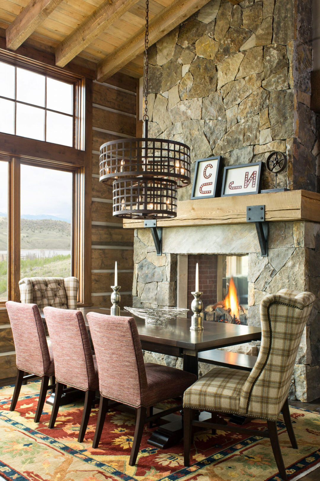 Rustic Mountain Dining Room with Stately Stone Covered Fireplace and Playful Plaid Upholstery